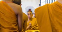 O que fazer em Chiang Mai: um monge budista sentado de frente para a câmera, com outros monges ao redor dele enquadrando a foto.