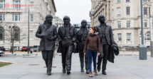 O que fazer em Liverpool: uma mulher andando na frente das 4 estátuas dos Beatles em Liverpool