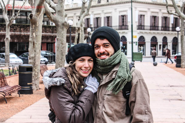 Um casal brasileiro, ela loira, ele moreno, usando roupas de frio monotemáticas, na Plaza Constituición, em Montevidéu, no Uruguai.