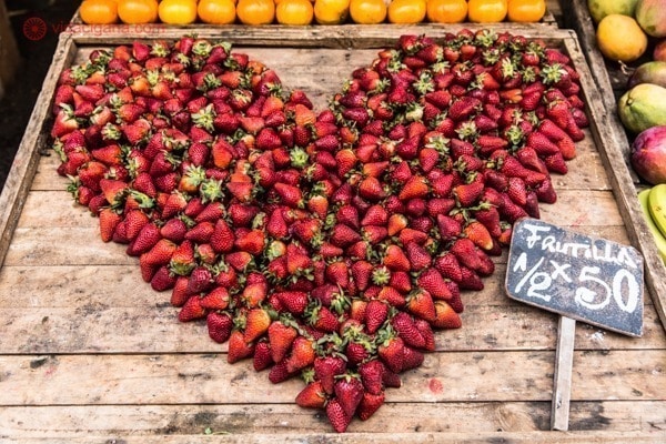 Morangos montados em uma banca de fruta em formato de coração, com uma placa escrito "frutillas", que significa "morangos" em espanhol. Essa banca fica em Montevidéu, no Uruguai.
