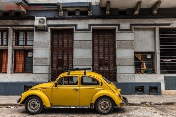 Um fusca amarelo está parada em uma rua de Montevidéu, a capital do Uruguai, em frente a casas na Ciudad Vieja.