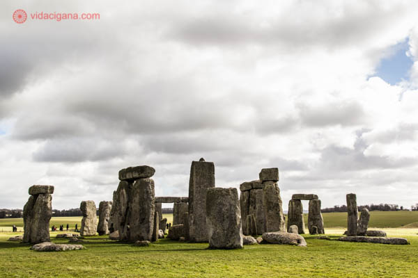 O monumento de Stonehenge, na Inglaterra, visto de outro ângulo, com as pedras em diferentes posições. O céu está nublado.
