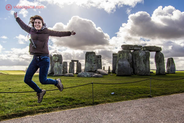 Uma mulher pulando alto na frente do monumento de Stonehenge, na Inglaterra.