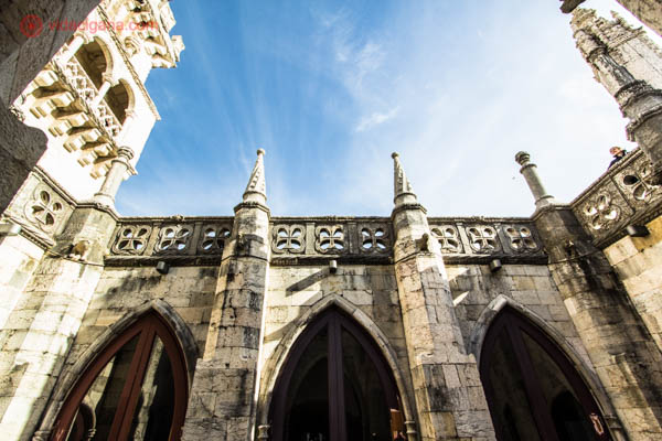 O pátio do baluarte da Torre de Belém, com sua arquitetura branca, vários arcos medievais. O céu é azul