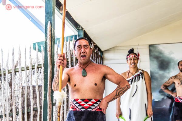 Um homem maori dançando e cantando cantos da cultura maori na Nova Zelândia em uma vila em Rotorua, Ilha Norte do país.