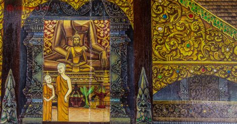 Um mural na parede em Chiang Mai onde dois monges estão pintados em formato de desenho, uma criança e um adulto, na entrada de um templo budista, com uma imagem de buda no interior.