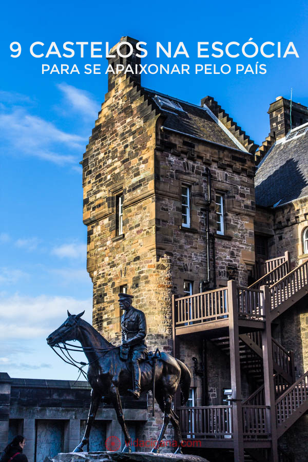 9 castelos na Escócia para se apaixonar pelo país. O interior do Castelo de Edimburgo, em uma de suas várias alas, com torres mais recentes, feitas de tijolos amarelados. Uma estátua equestre com um homem montando um cavalo se encontra no meio desse setor, na frente de uma torre com uma escada de madeira. O céu está azul.