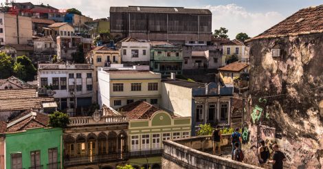A vista da Pequena África, no Rio de Janeiro, do alto dos Jardins Suspensos do Valongo. Várias casinhas de 2 andares coloridos podem ser vistos do topo, pessoas descem pela esquina do Morro da Conceição.