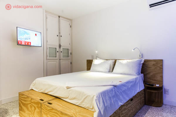 O maior quarto do Belga Hotel, com camas imensas, lençois brancos, paredes brancas e televisão.