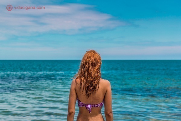 O que fazer em Belize: Uma mulher com cabelos longos ruivos olha o Mar do Caribe, em Belize