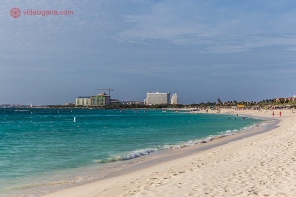 O que fazer em Aruba: Foto da orla de Eagle Beach, uma das praias mais conhecidas de Aruba, com águas azuis e alguns hotéis ao longe.