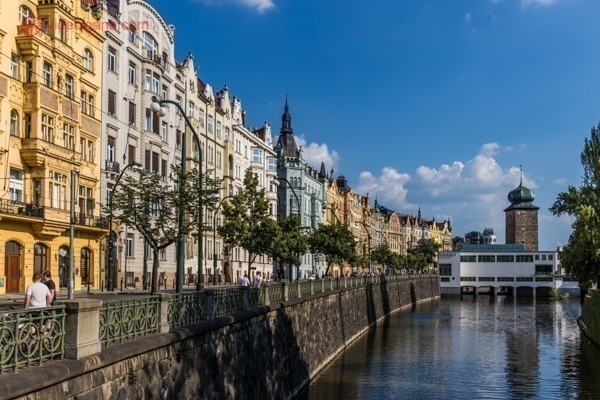 Onde ficar em Praga: O Rio Moldava cercado de prédios antigos e coloridos, e com árvores bem verdes. O céu está azul