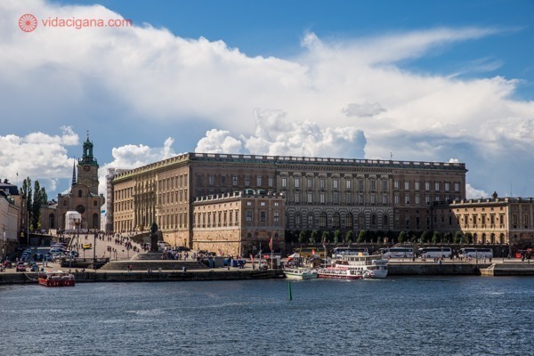 O que fazer em Estocolmo: O palácio de estocolmo na beira da água, bem reto em bloco. O céu está azul, cheio de nuvens