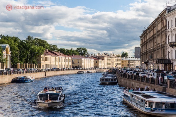 O que fazer em São Petersburgo: Um barco navega por um dos canais do Rio Neva, com lindos prédios amarelos no entorno.