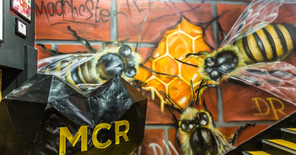 O que fazer em Manchester: Uma parede com um mural pintado, cheio de abelgas em uma comeia, representando o povo de Manchester.