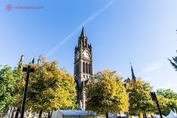 Vista da torre do relógio do prédio da prefeitura de manchester em meio as árvores da praça Albert