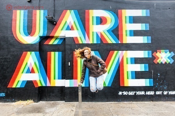 Onde ficar em Dublin: uma menina ruiva pulando em frente a um muro com street art em Portobello
