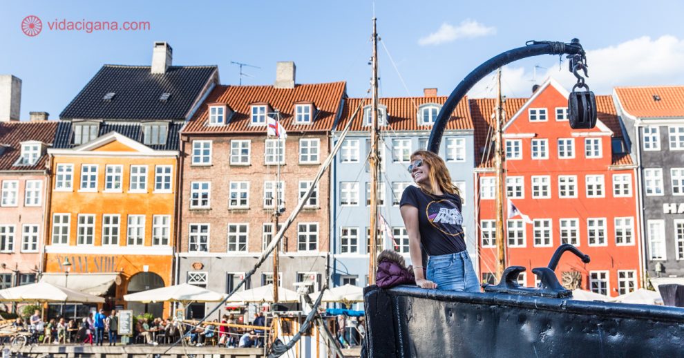 O que fazer em Copenhague: uma mulher na proa de um barco aportado no porto de Nyhavn, a região mais famosa de Copenhague