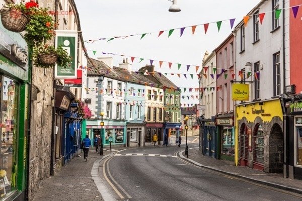 Roteiro Irlanda: A rua principal da cidade de Kilkenny, na Irlanda, cheia de casinhas coloridas e bandeiras penduradas
