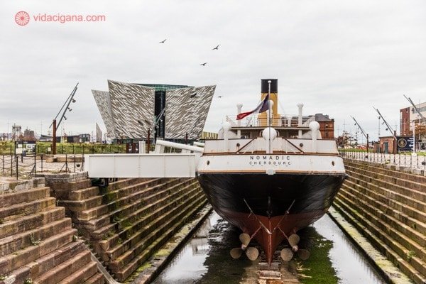 O que fazer em Belfast: o SS Nomadic, um pequeno navio com uma chaminé somente, com o museu lá ao fundo