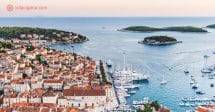 Hvar vista do alto da fortaleza da cidade, com seus telhados ocre, barcos ancorados no porto, mar azul e ilhas espalhadas. a foto foi tirada durante o pôr do sol