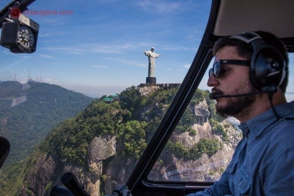 O piloto a bordo do helicóptero com o Cristo atrás