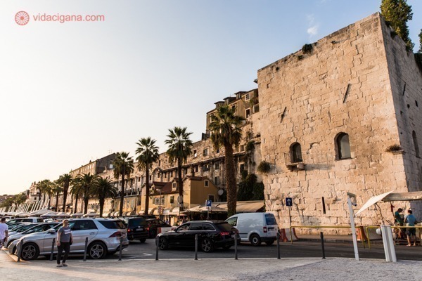 O que fazer em Split: a riva na base das muralhas do palácio, com suas várias palmeiras e alguns carros estacionados