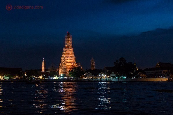 Wat Arun visto iluminado durante a noite a partir do rio