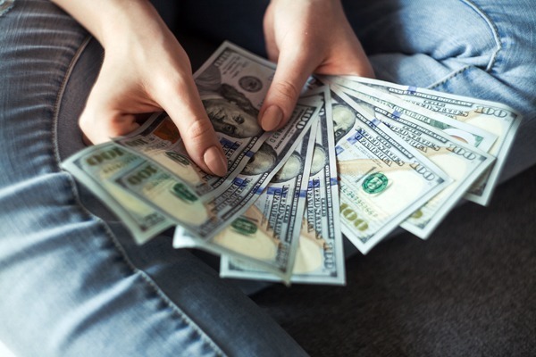 Enviar dinheiro para o exterior: várias notas de dólares em mãos femininas