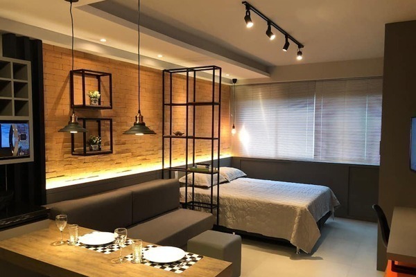 Airbnb em Curitiba: uma cama de casal com uma mesa, iluminação baixa e intimista