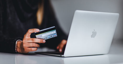 Como enviar dinheiro para Portugal: uma mulher segurando um cartão de crédito em frente ao computador
