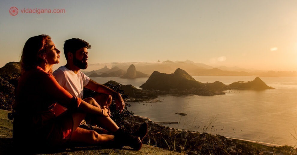Onde ficar em Niterói: um casal sentado no Parque da Cidade, em Niterói, admirando o pôr do sol