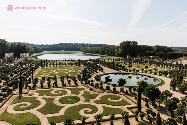 Um dos jardins do Palácio de Versailles com um lago imenso ao fundo