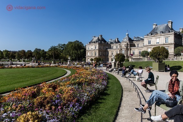 O Jardim de Luxemburgo e as pessoas sentadas no sol em frente ao palácio de luxemburgo