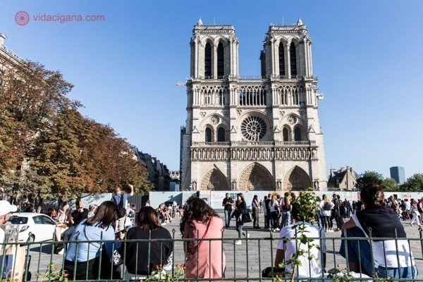 A Notre Dame vista ao longe, fechada após o incêndio, mas mesmo assim, cheia de pessoas ao seu redor
