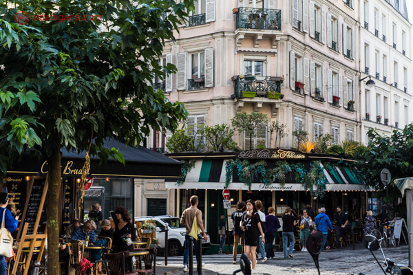 Uma rua de Montmartre com prédios lindos e restaurantes com decoração incrível, cheia de natureza