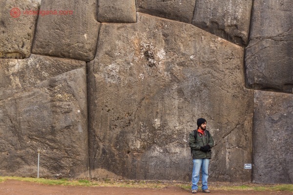 Um homem na frente de uma pedra enorme de 11 ângulos em Sacsayhuaman