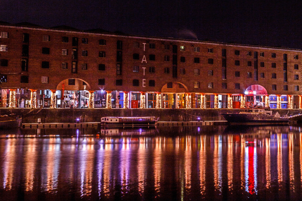O Tate Liverpool no Albert Dock durante a noite, todo iluminado.