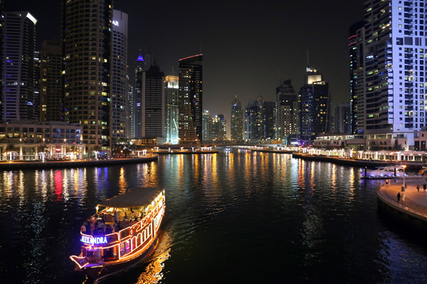 Dubai Marina à noite, com barcos passeando na marina