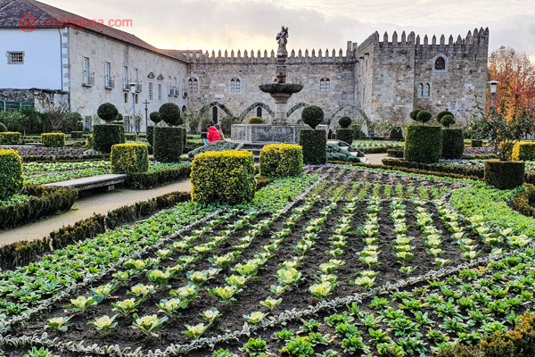 O Jardim de Santa Bárbara cheio de verde, com um prédio medieval no fundo