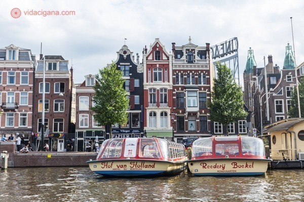 O que fazer em Amsterdam: prédios coloridos em frente aos canais de Amsterdam, com 2 barcos ancorados