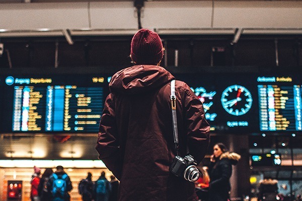 Um homem olhando um painel numa estação de trem