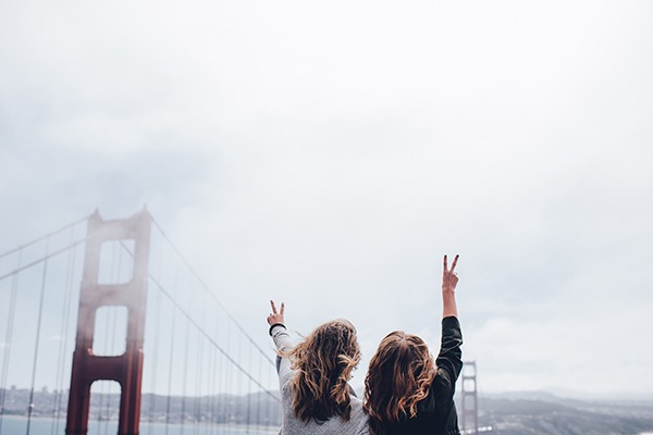 Duas crianças fazendo o símbolo da paz com os dedos na frente da Golden Bridge, em São Francisco