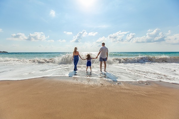 O que é seguro viagem: um casal com uma criança em frente ao mar