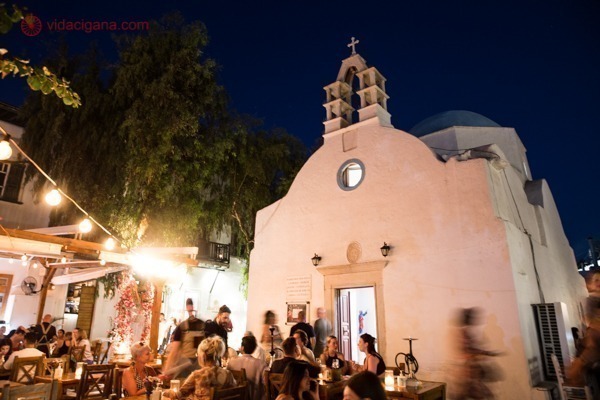 O que fazer em Mykonos: uma igreja em Little Venice com várias pessoas comendo em frente