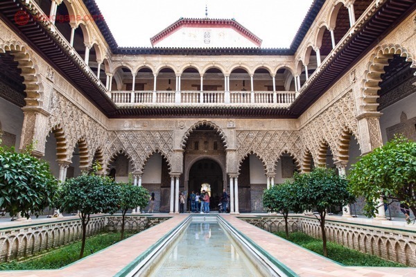 O interior do Real Alcazár de Sevilha, com suas colunadas islâmicas e uma piscina em sua extensão
