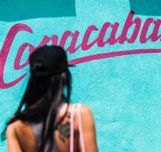 Onde ficar em Copacabana: uma mulher de costas a caminhar para uma parede azul onde se vê escrito Copacabana