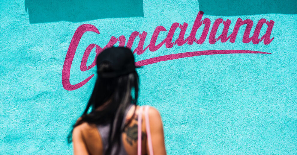 Onde ficar em Copacabana: uma mulher de costas a caminhar para uma parede azul onde se vê escrito Copacabana