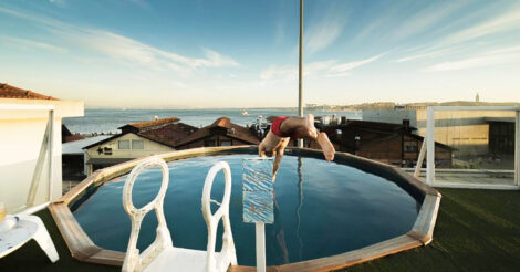 Hostel em Lisboa: um homem saltando pra dentro de uma piscina com vista para o Rio Tejo