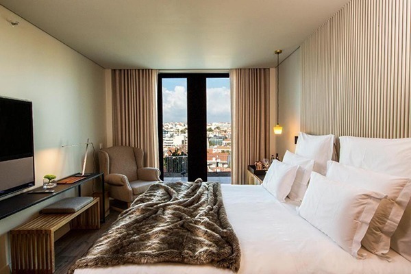 Um quarto de hotel com linda vista, com cama grande com lençóis brancos e cobertor esverdeado